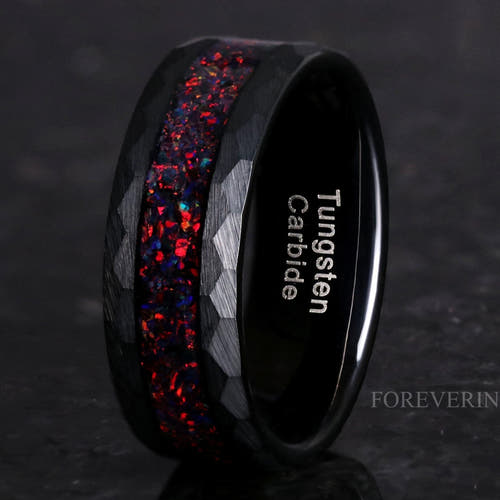 8mm hammered black tungsten wedding band with crushed black fire opal inlay, standing at an angle