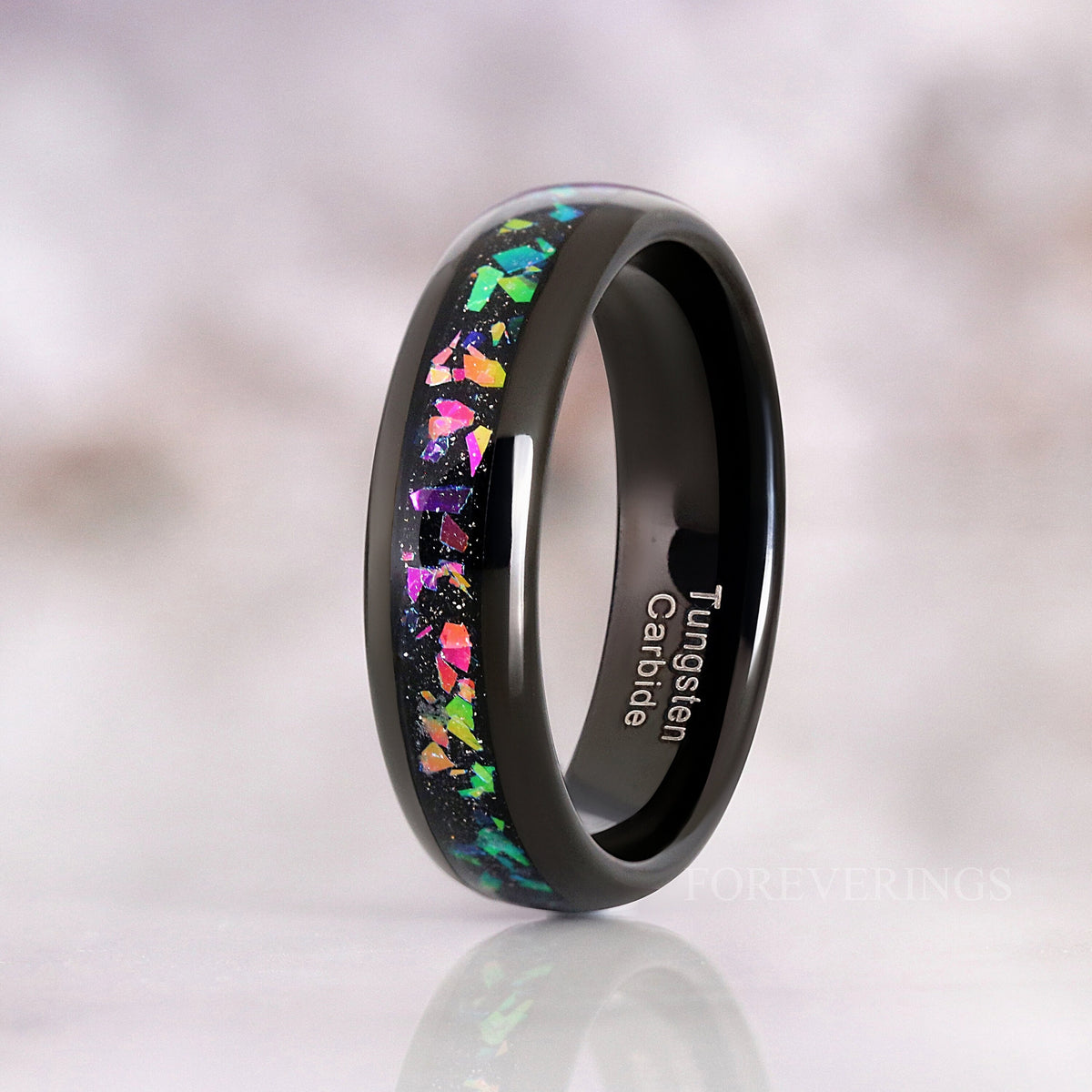 6mm black tungsten supernova ring standing on edge, pink and green flakes in the inlay