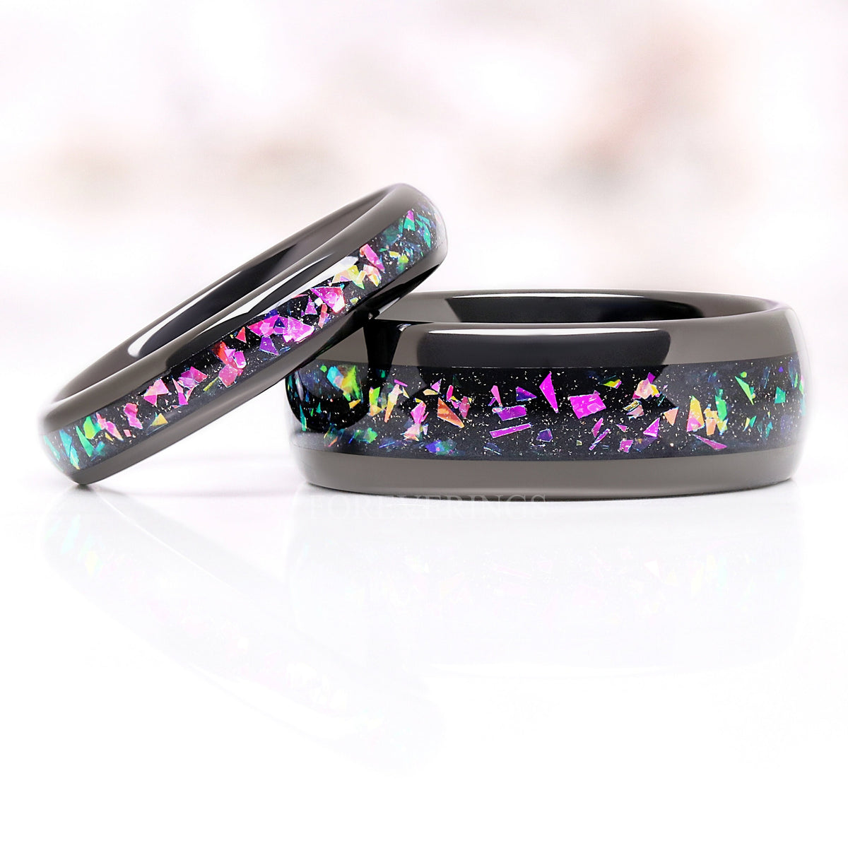 Thin black supernova band leaning on a wide one with the same inlay, reflection below