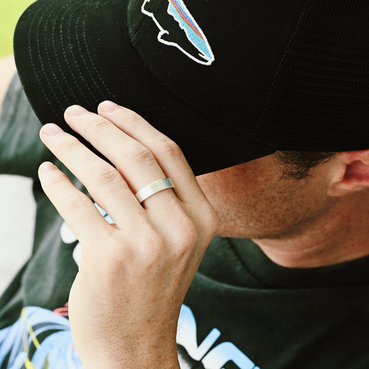 Brushed sterling silver band worn on a man's hand, wider view