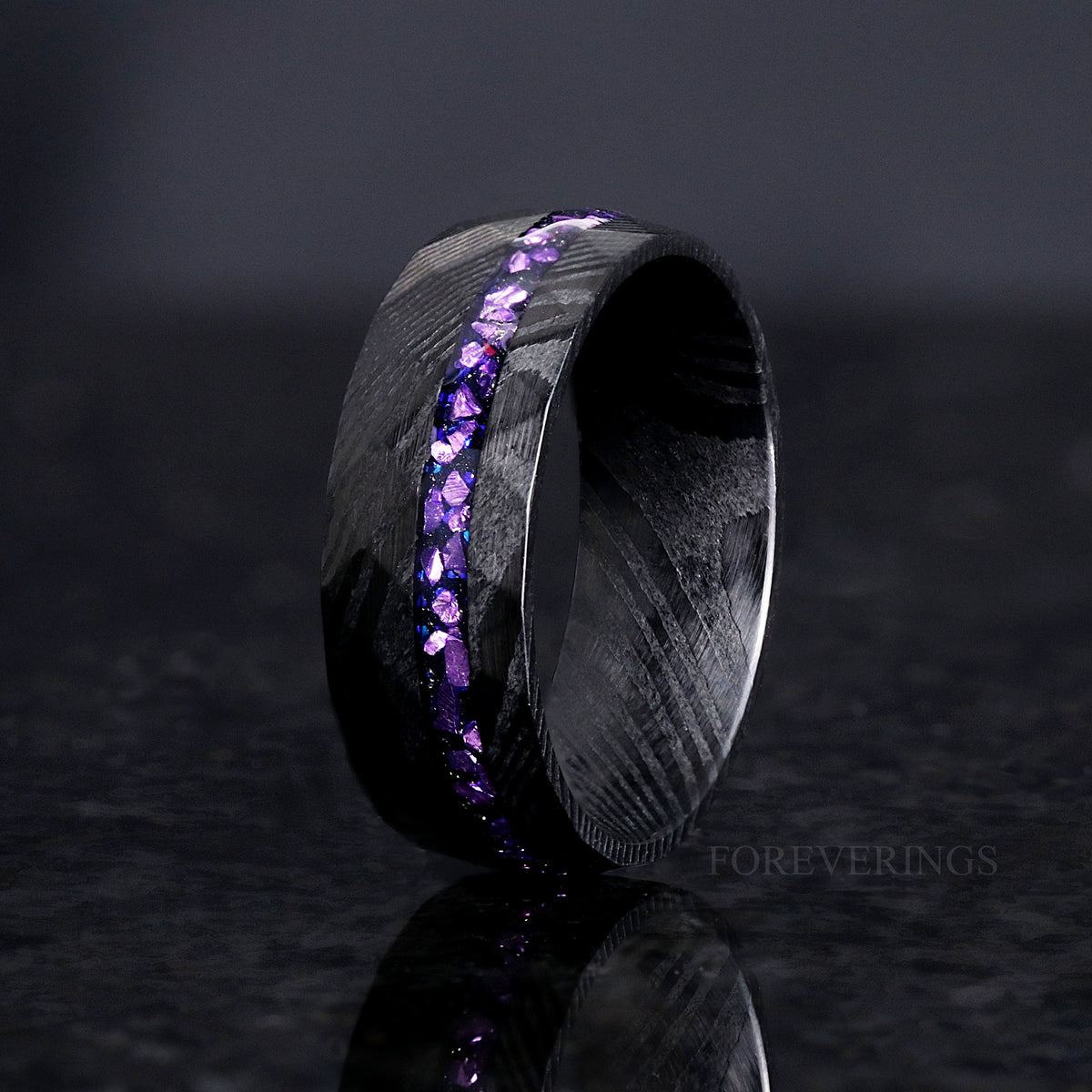 Men's 8mm faceted black Damascus steel ring with a purple alexandrite stripe, standing at an angle