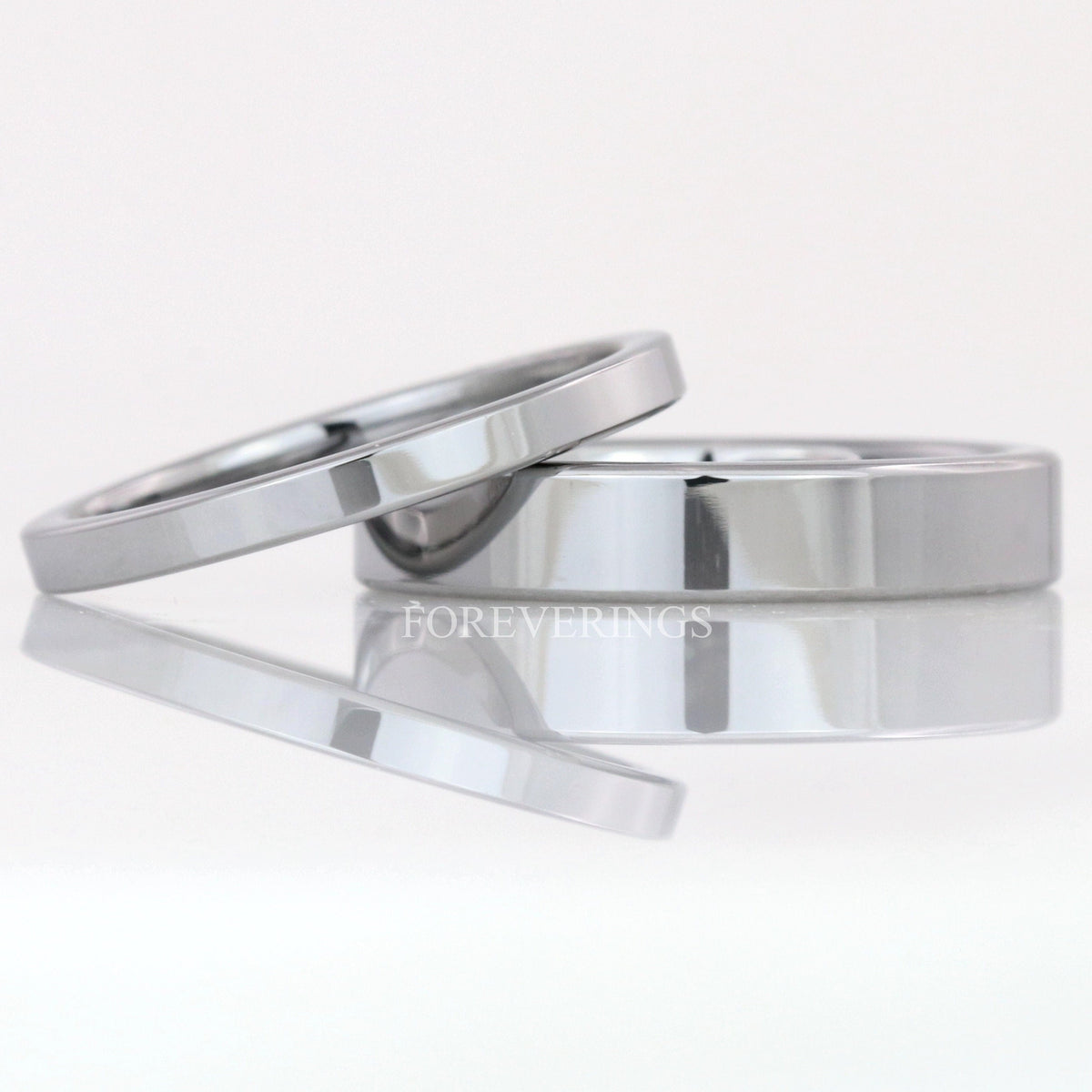 2mm and 4mm flat silver tungsten wedding bands, the thin band leaning on the wider one