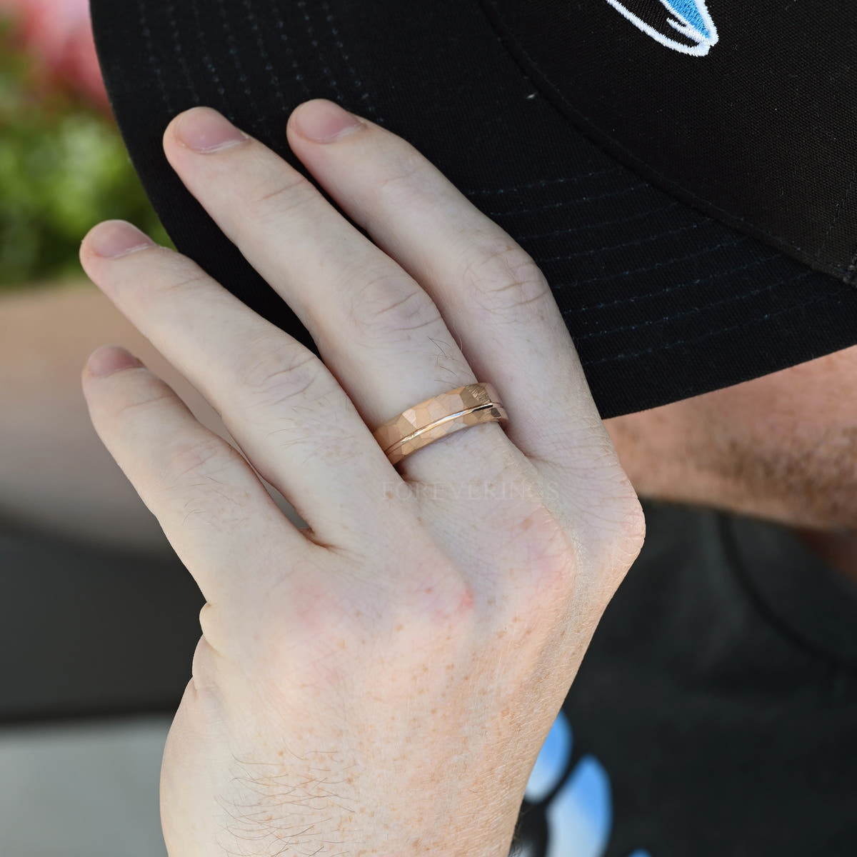 Hammered rose gold tungsten band with offset groove worn on a man's hand