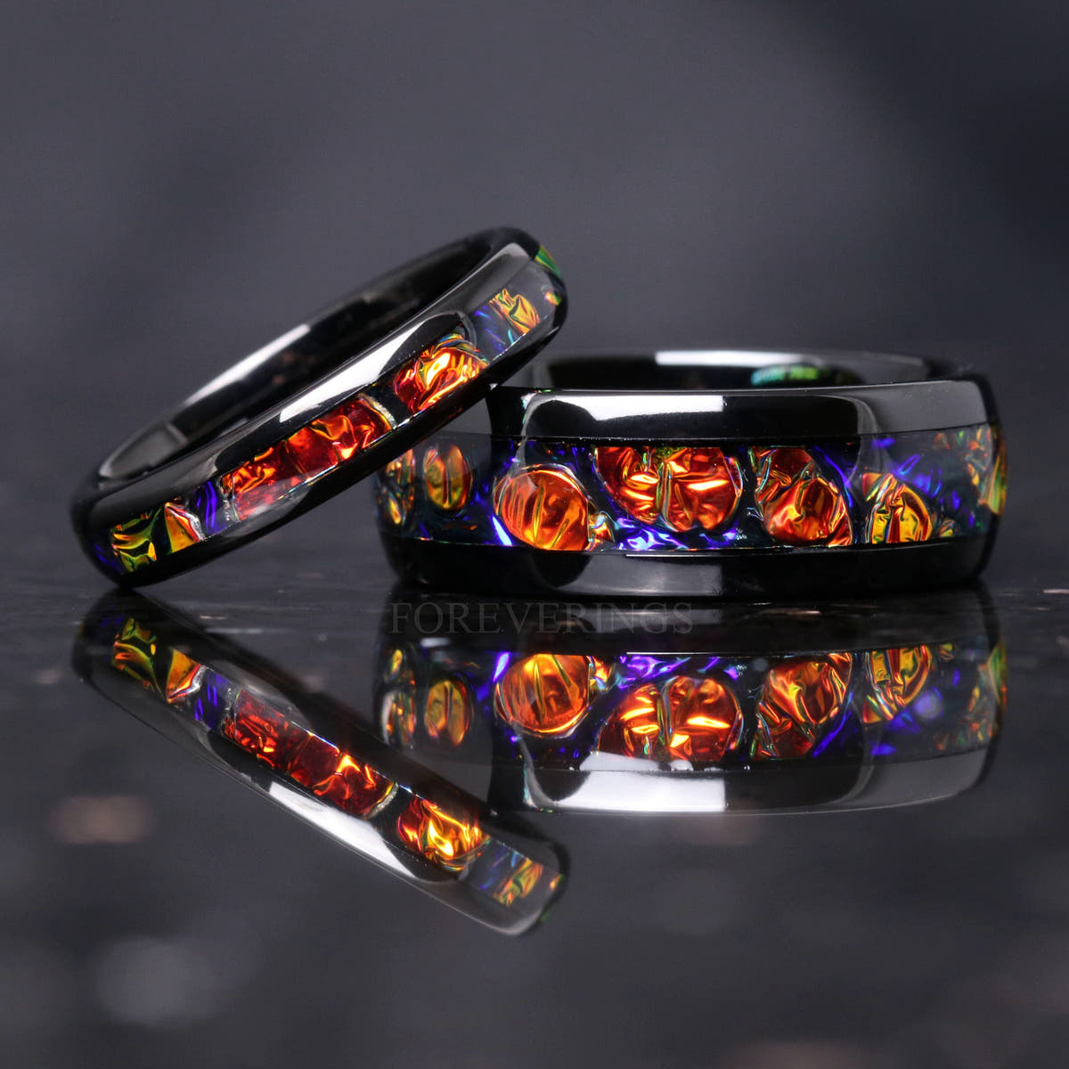 4mm black tungsten dichrolam ring leaning on a wider band with the same red dichrolam inlay