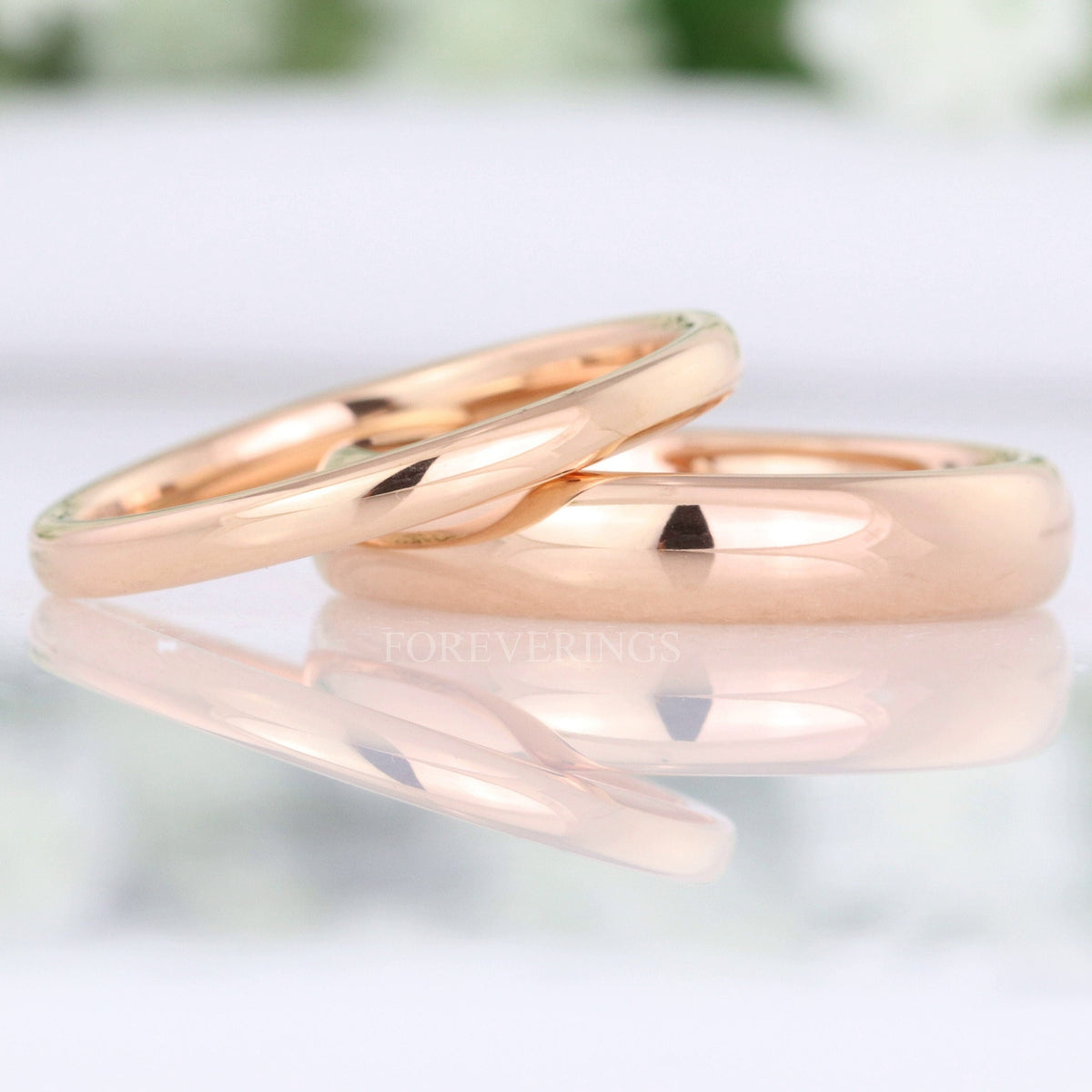 Minimalist rose gold tungsten wedding bands in 2mm and 4mm, polished dome, leaning together