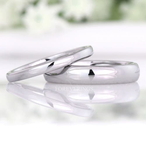 Minimalist 2mm and 4mm polished silver tungsten wedding bands, the thin band leaning on the wider one