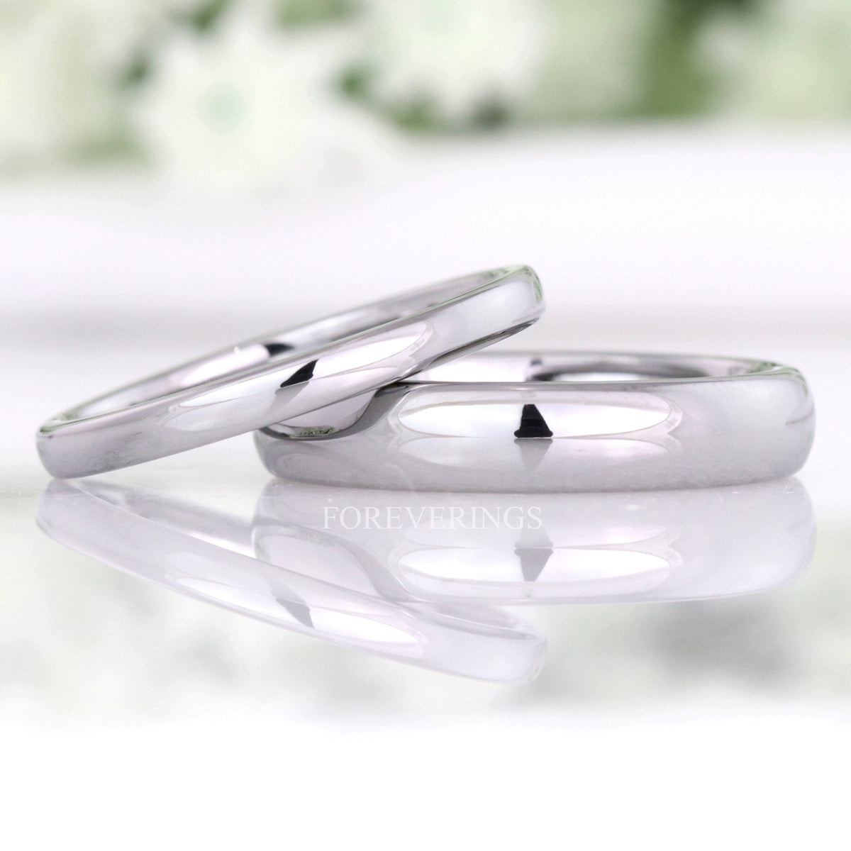 Minimalist 2mm and 4mm polished silver tungsten wedding bands, the thin band leaning on the wider one