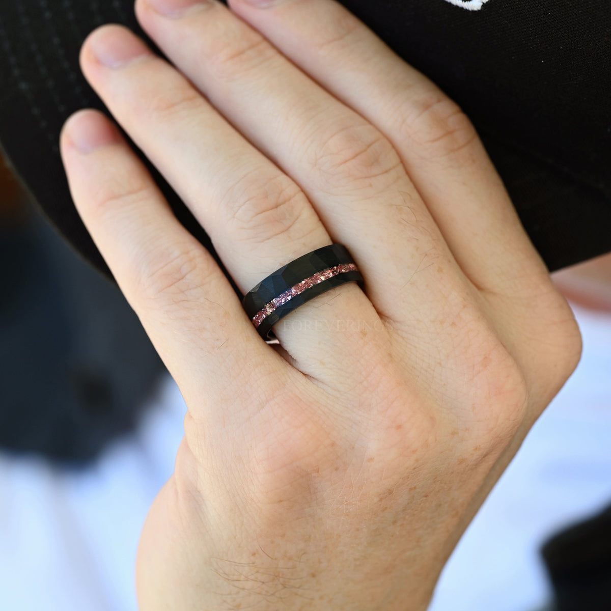Men's 8mm black hammered tungsten band with morganite inlay, worn on a hand
