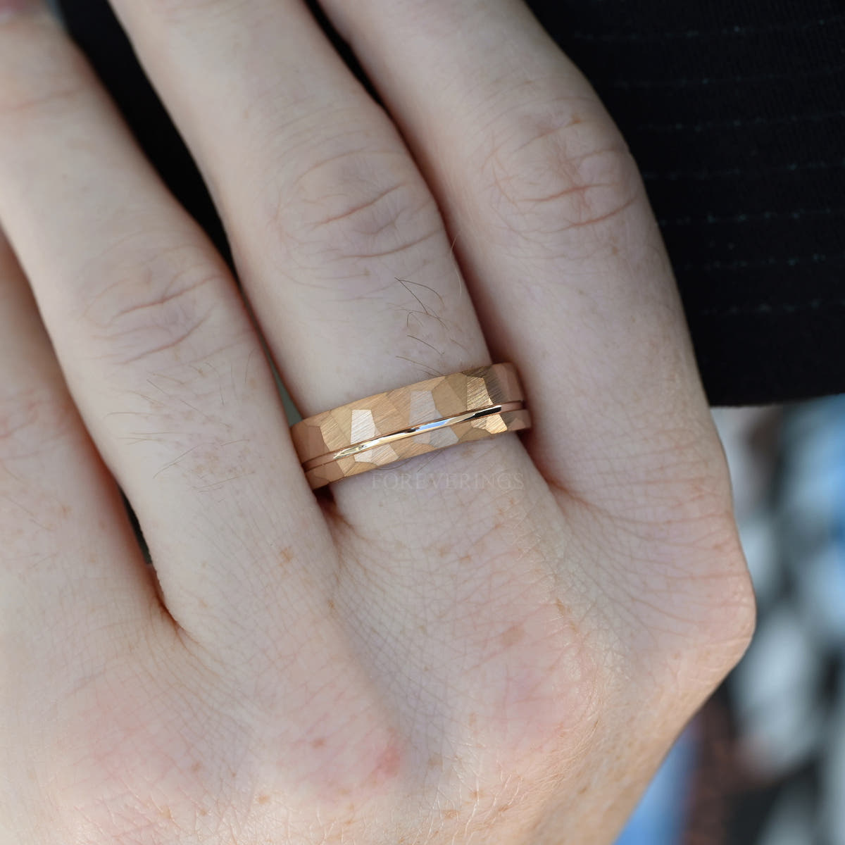 Men's 7mm rose gold hammered band on a hand, close view of the groove