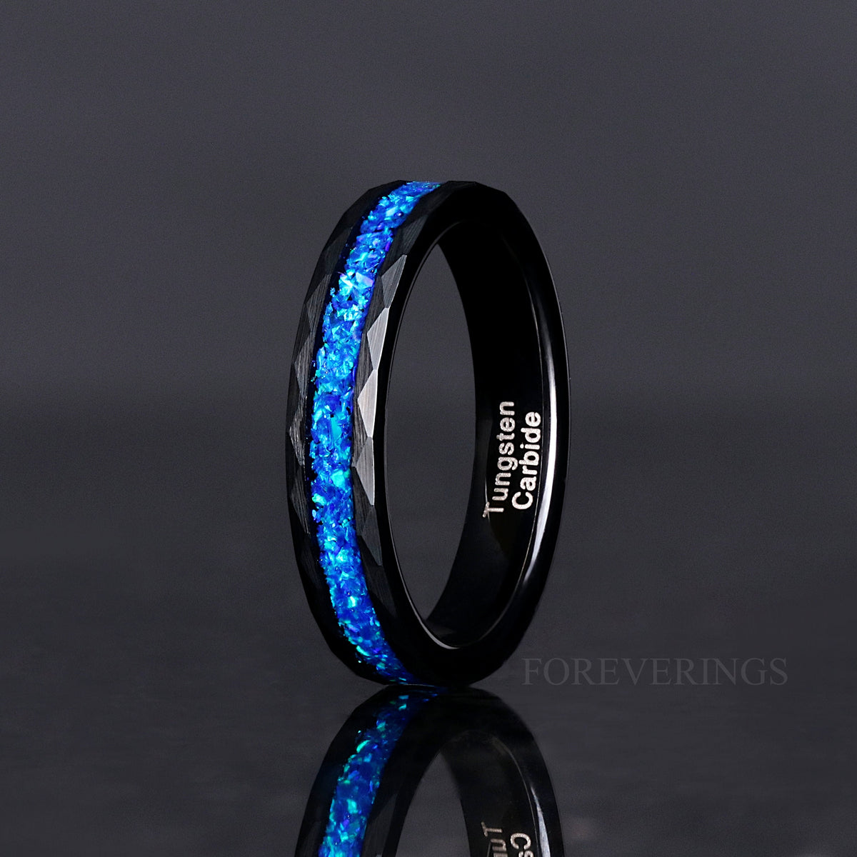 Women's 4mm hammered black tungsten ring with blue fire opal inlay, standing on edge