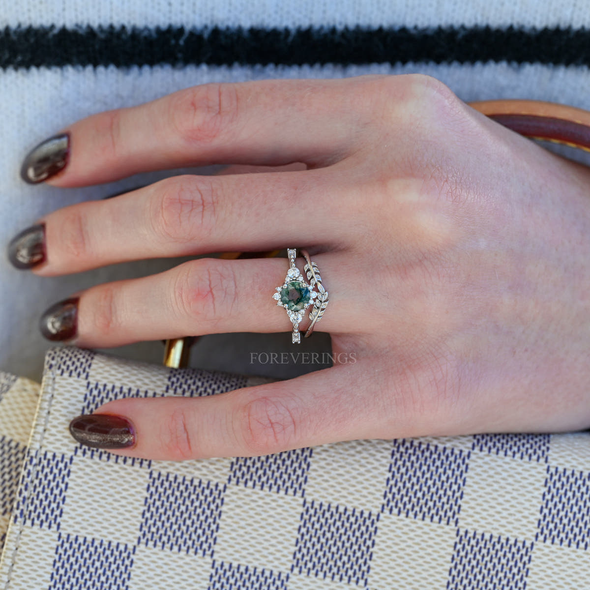 Women's sterling silver moss agate engagement ring worn on a hand