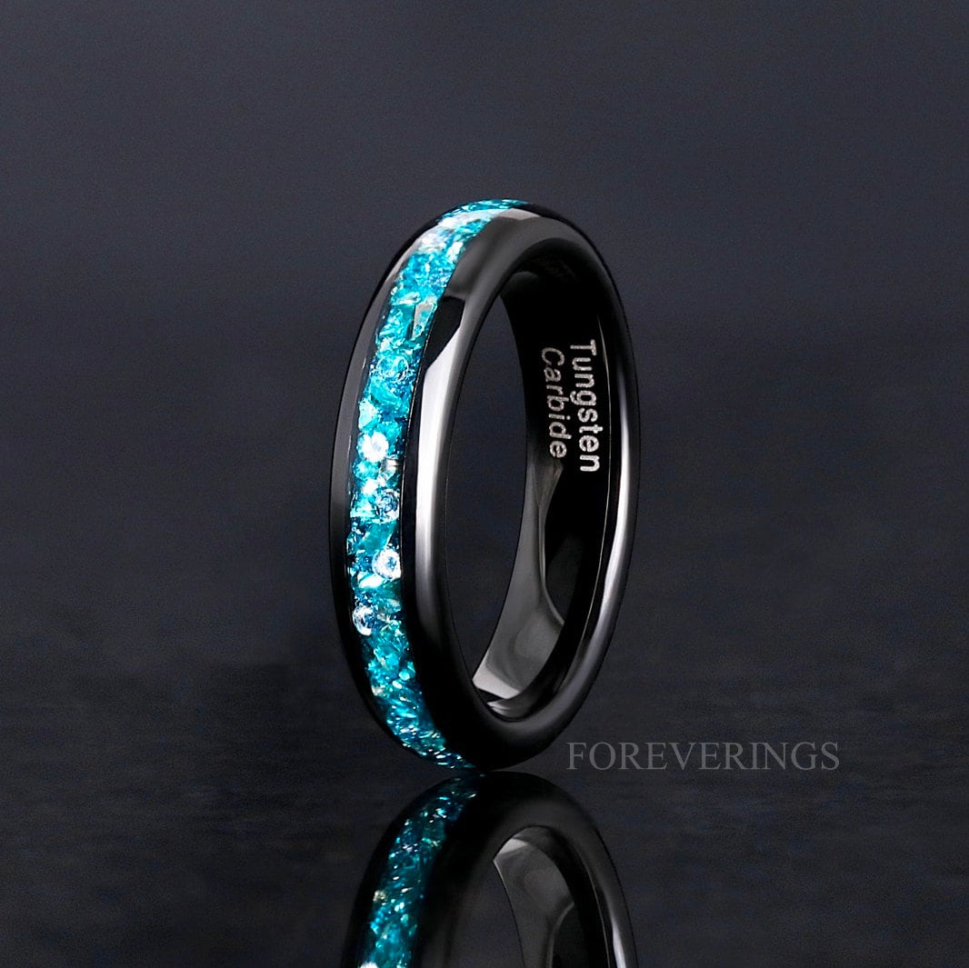 Women's 4mm black tungsten band with crushed aquamarine inlay, standing on edge