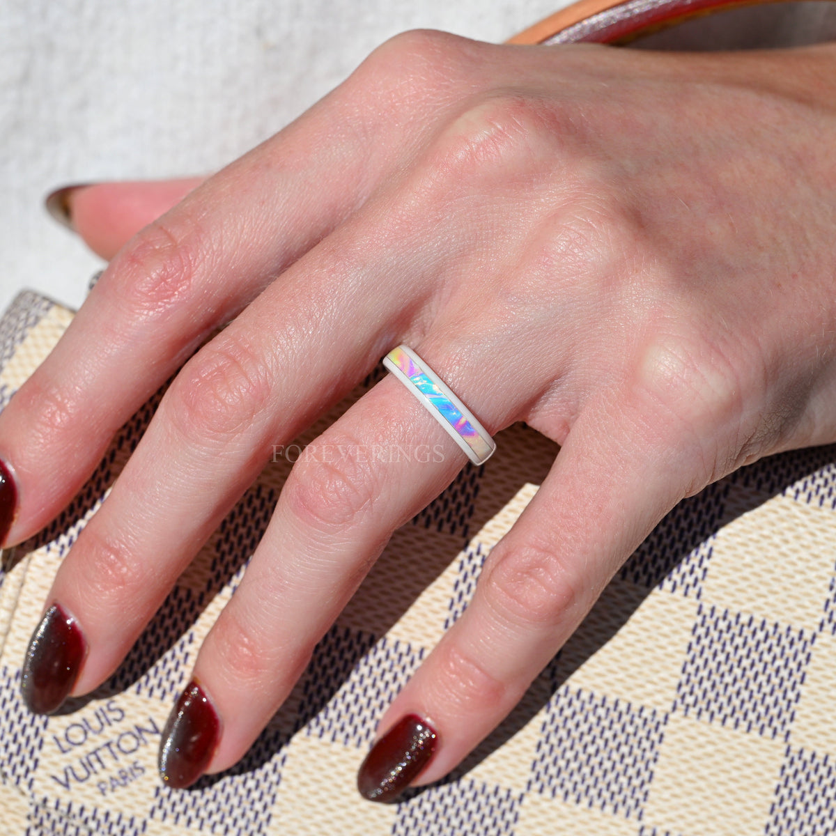 White ceramic dichrolam band worn on a woman's hand, close view