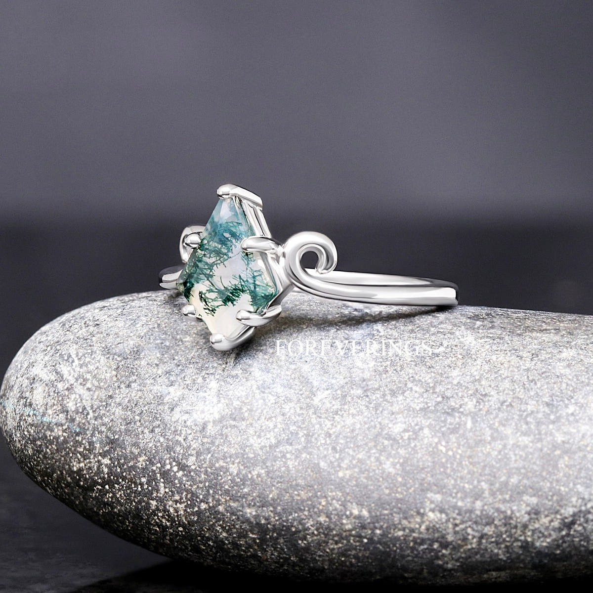 Sterling silver moss agate ring with twirl band at an angle, side view