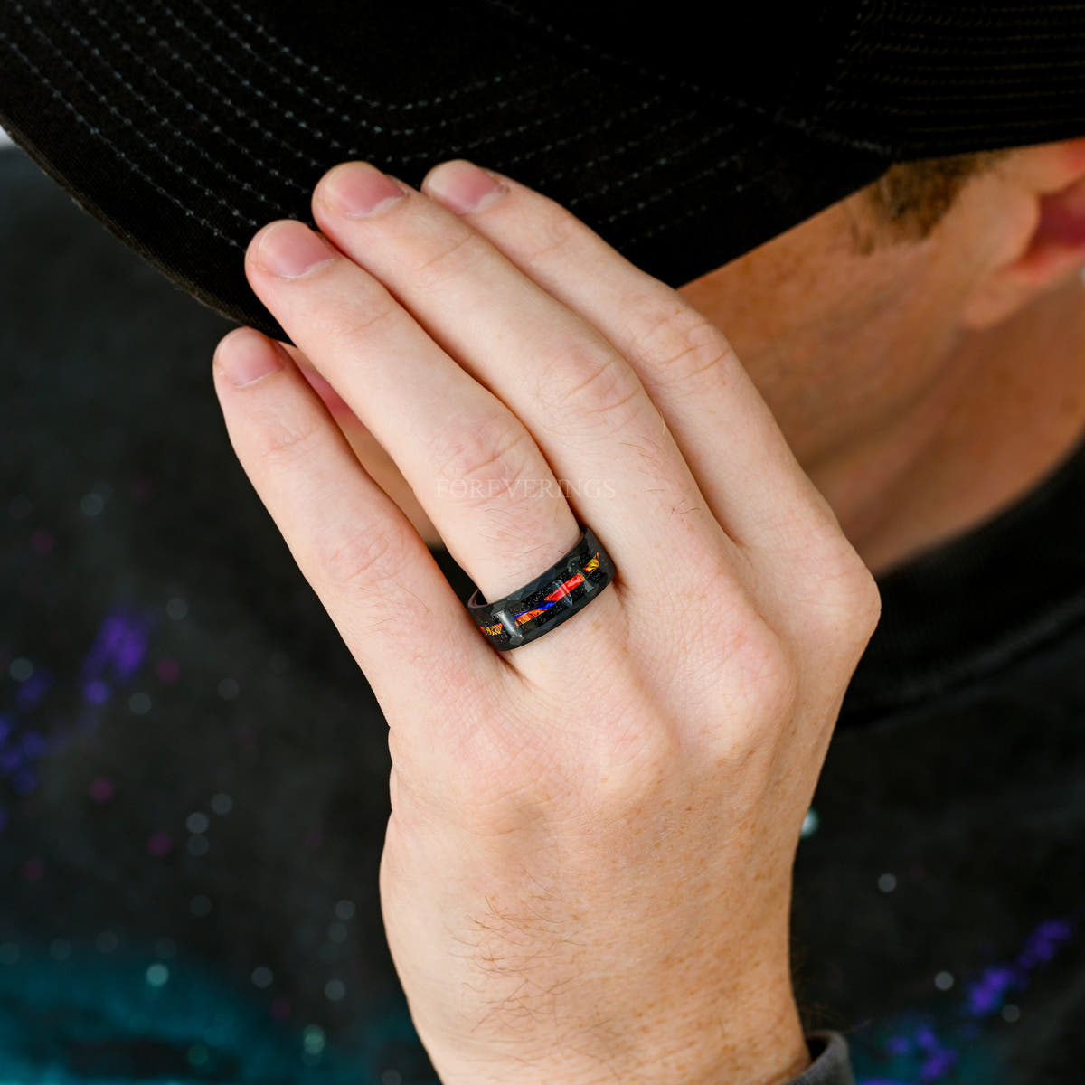 Hammered black tungsten dichrolam ring worn on a man's hand