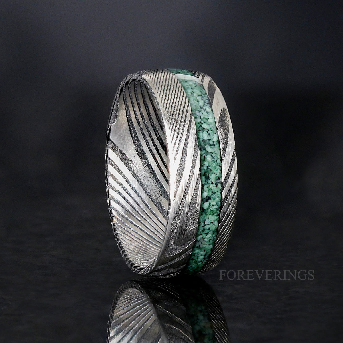 Men's 8mm Damascus steel ring with an offset crushed moss agate stripe, standing upright