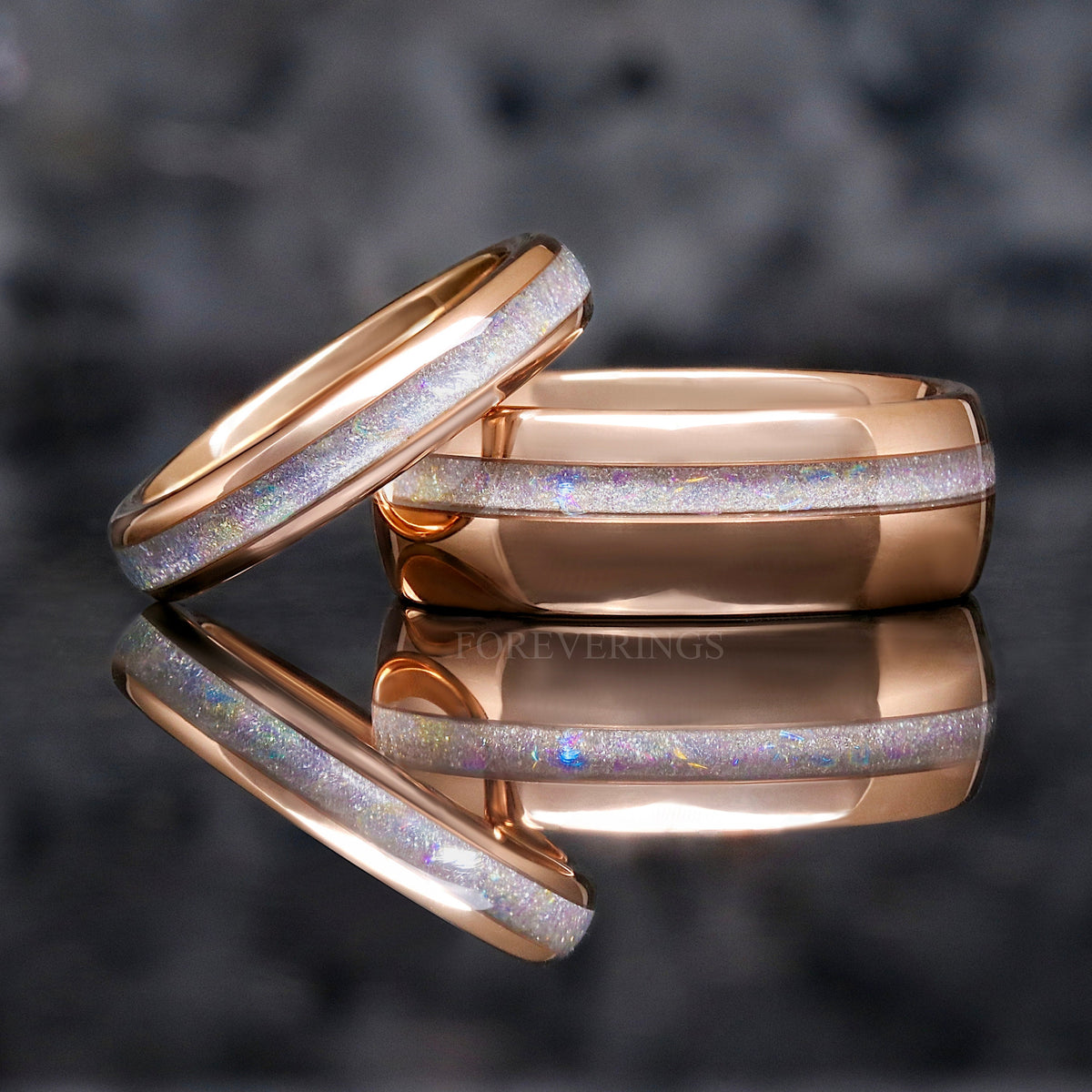 4mm rose gold tungsten ring with moonstone inlay leaning on a wider rose gold moonstone ring
