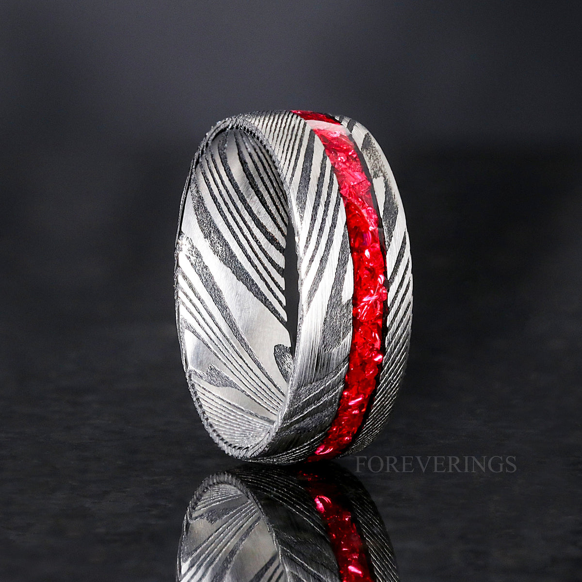 Men's 8mm Damascus steel band with a crushed garnet stripe, standing at an angle