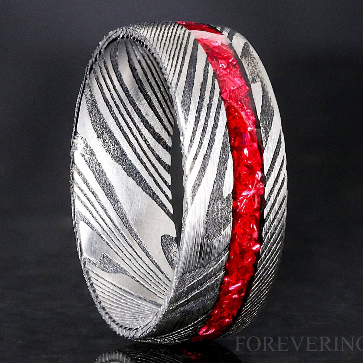 Men's 8mm Damascus steel ring with an offset crushed garnet inlay, standing close-up