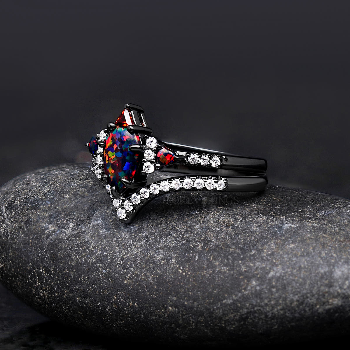 Angled side view of the black fire opal engagement ring and curved band with white stones