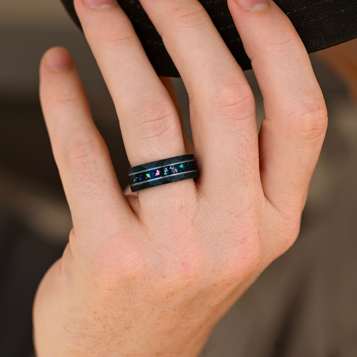 Men's black and silver tungsten band with multicolor crushed stone inlay worn on a hand