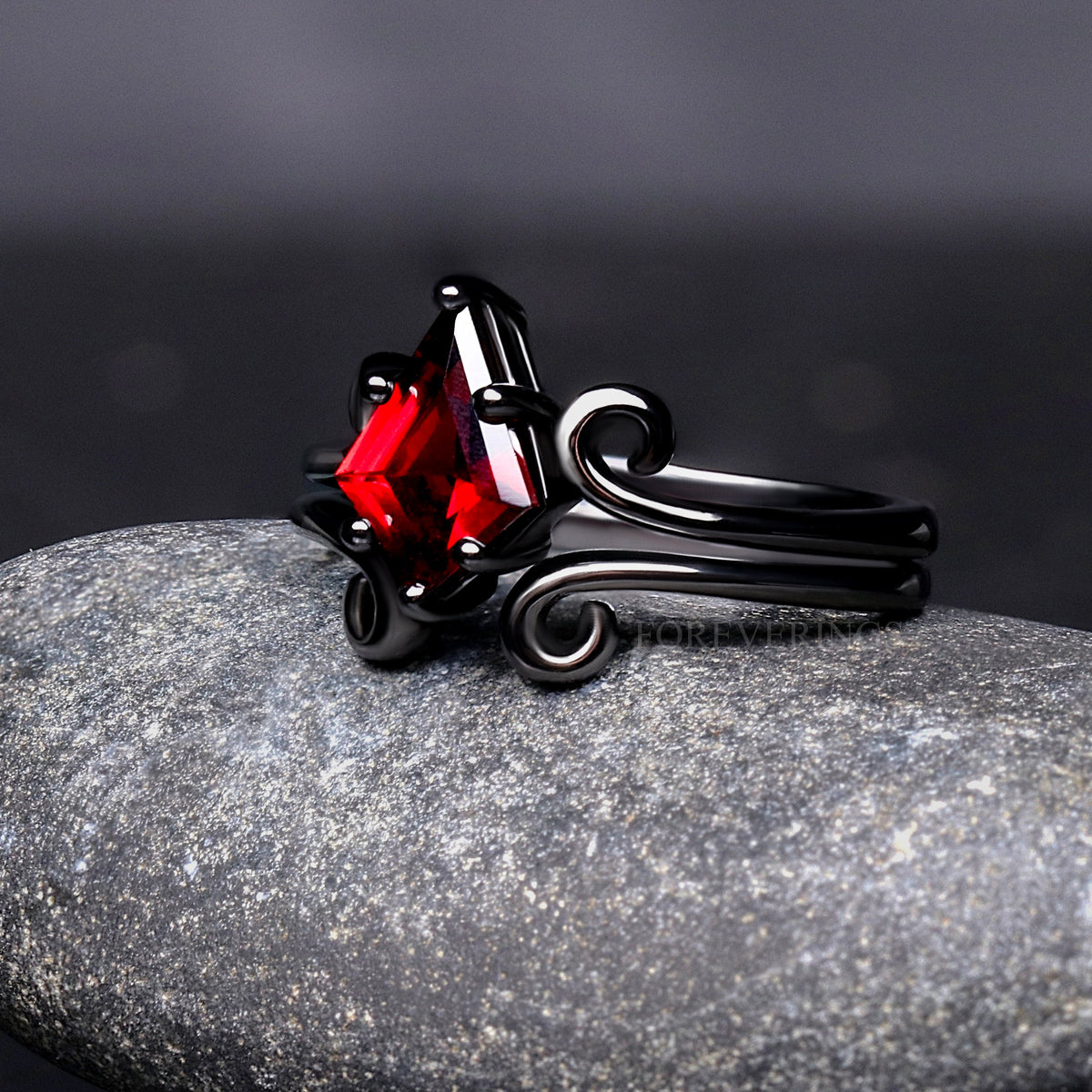 Black sterling silver garnet ring angled from the side, showing the swirl band