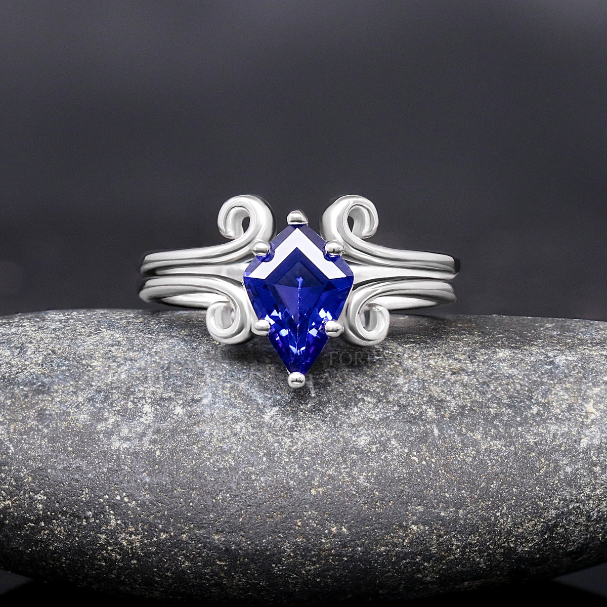 Kite-cut blue sapphire ring in sterling silver with curling swirl details, front view