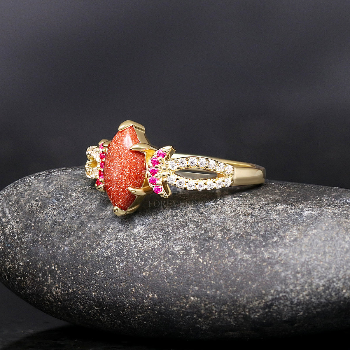 Red sandstone engagement ring angled to show the split gold band with small stones