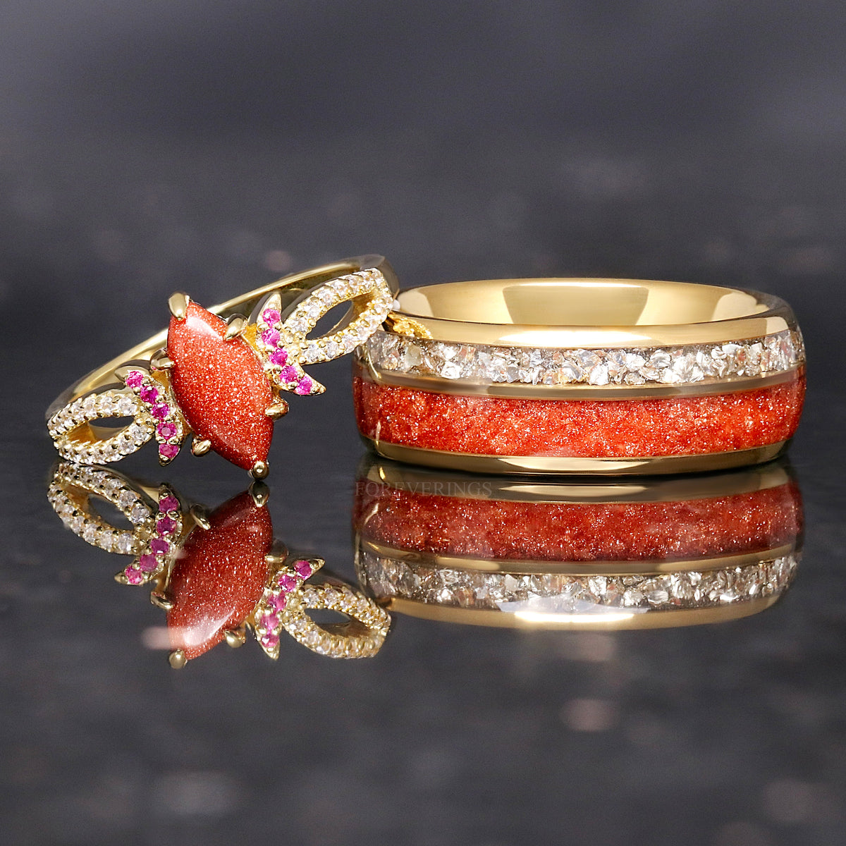 8mm gold tungsten band with red sandstone inlay beside a gold engagement ring with a marquise red stone