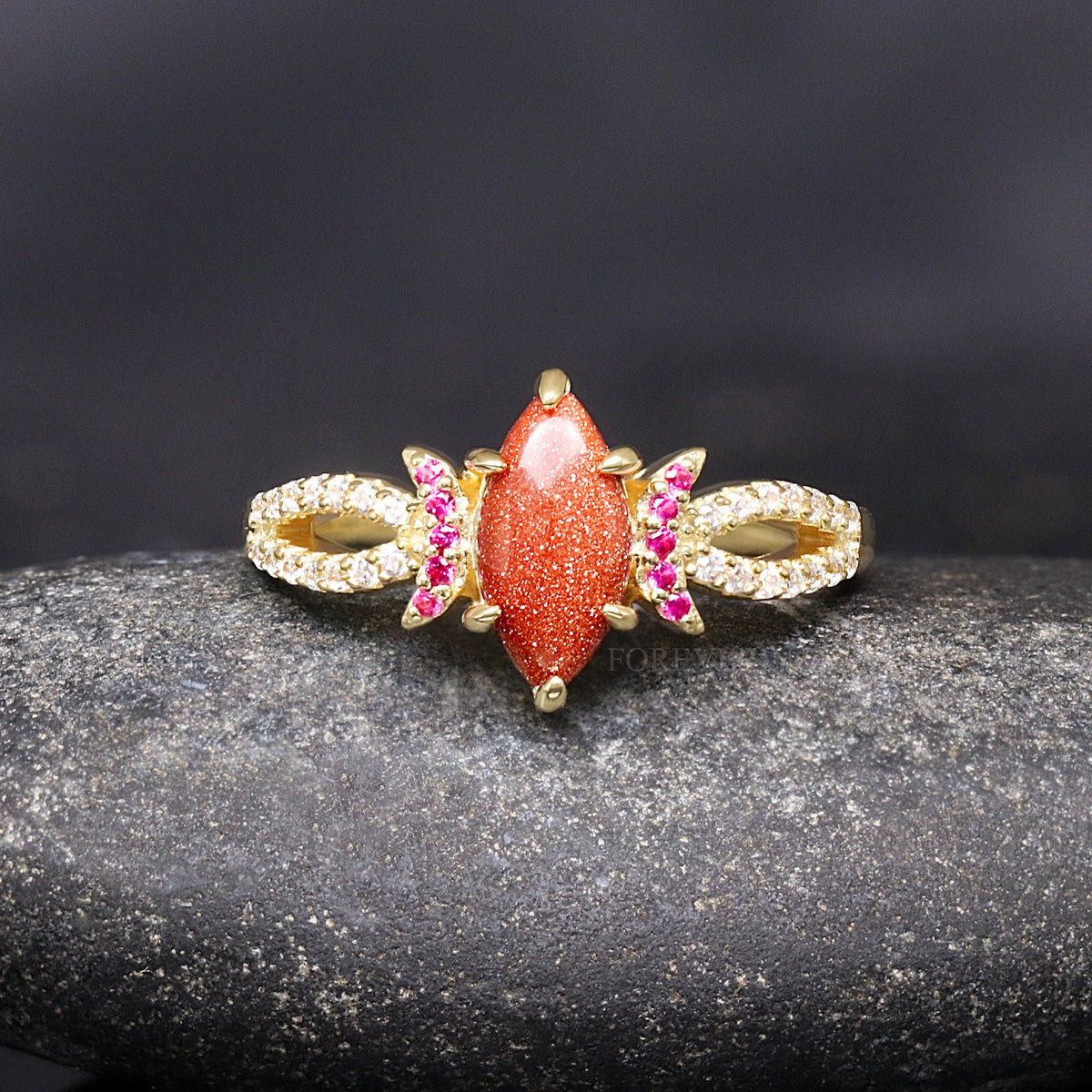 Women's gold sterling silver engagement ring with a marquise red sandstone and ruby accents, front view