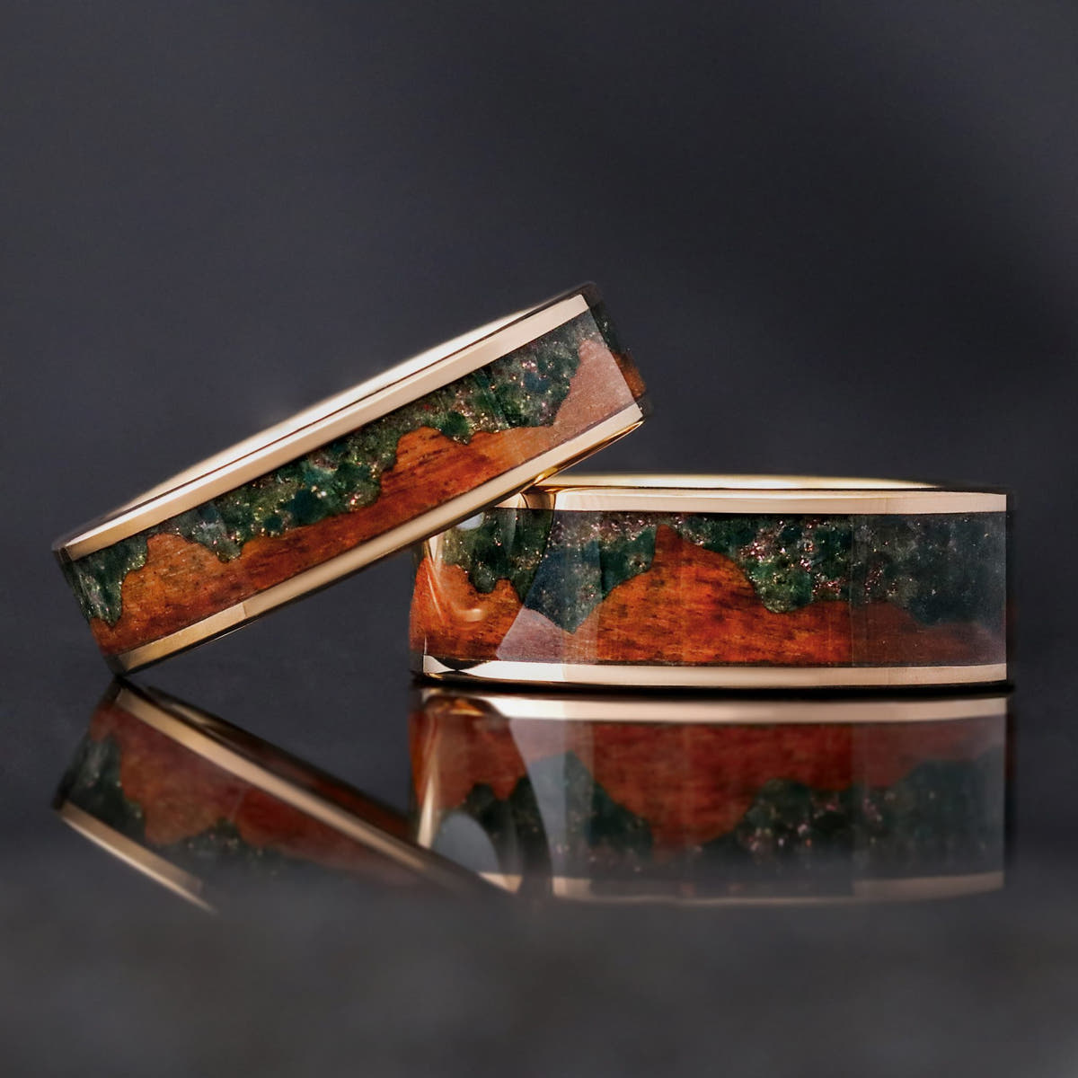 6mm and 8mm rose gold tungsten rings with moss agate and koa wood inlay, the 6mm leaning on the 8mm