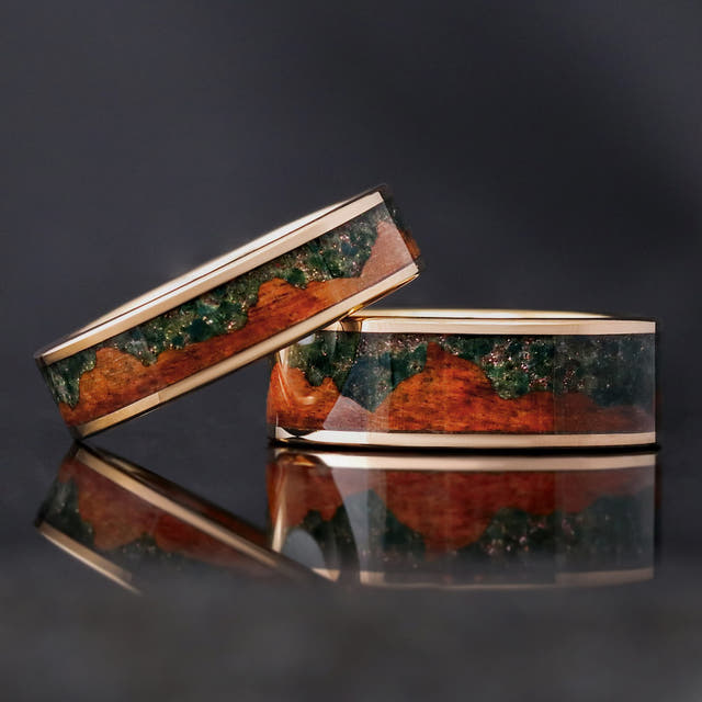 6mm and 8mm rose gold tungsten rings with moss agate and koa wood inlay, the 6mm leaning on the 8mm