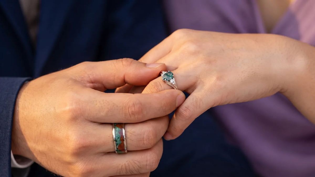 Couple exchanging matching promise rings - he slides hers on while wearing his turquoise inlay band