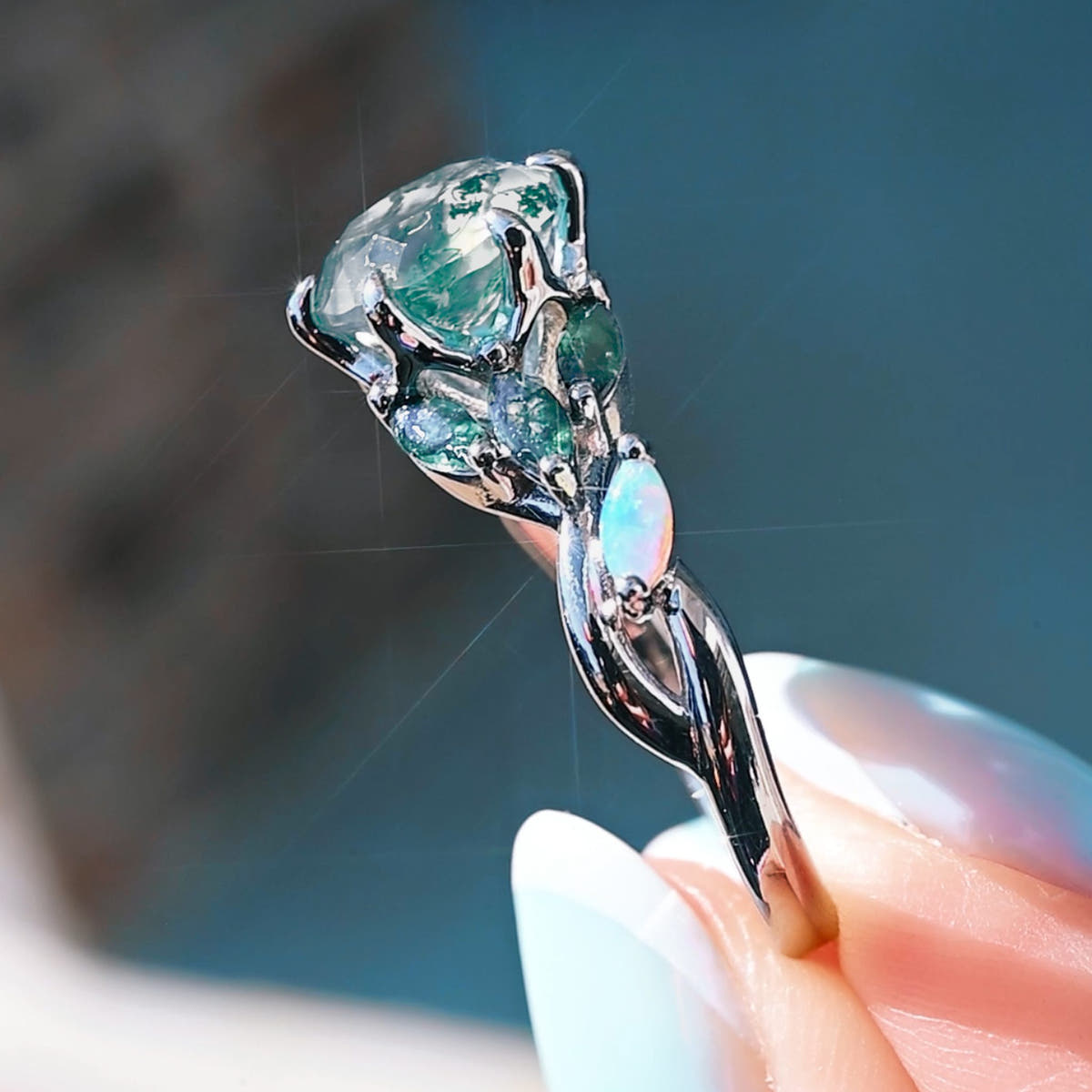 Moss agate engagement ring in side view, showing the silver vine band and marquise opal