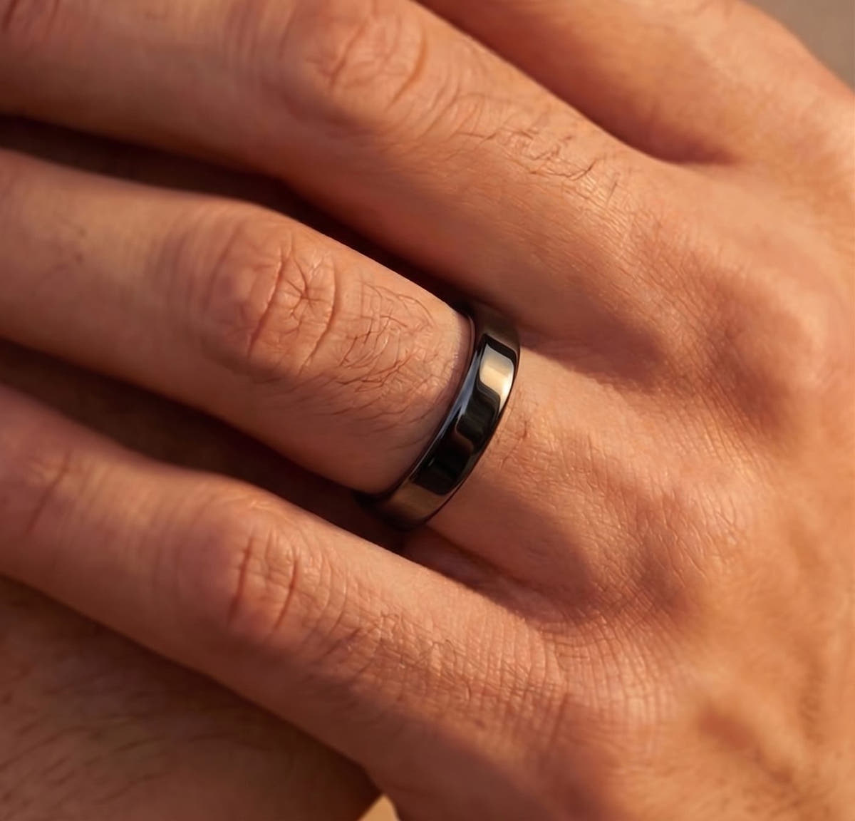Thin black tungsten wedding band worn on a man's hand