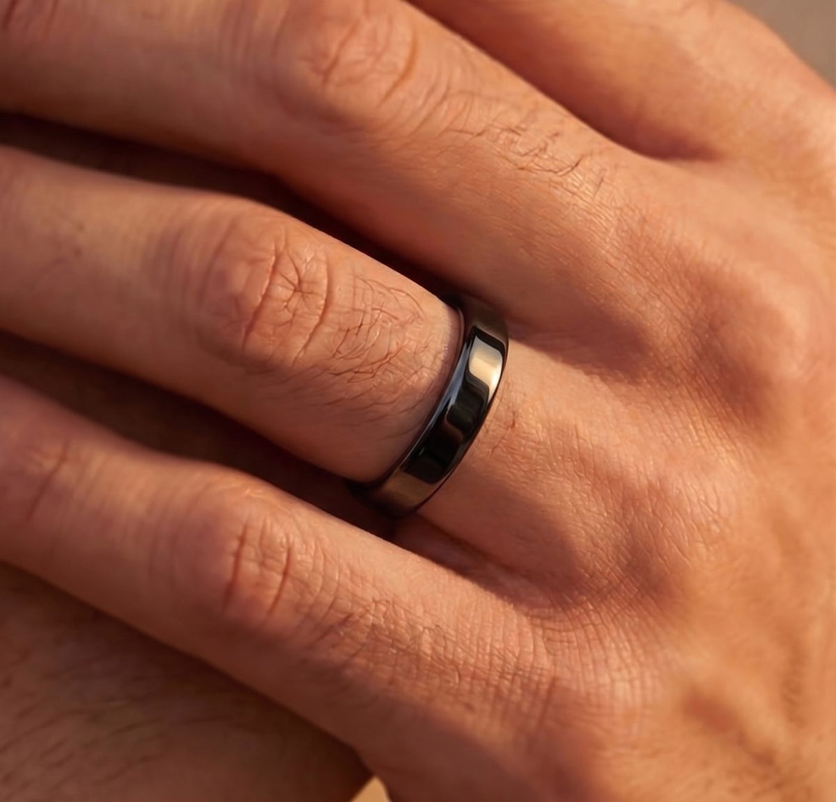 Thin black tungsten wedding band worn on a man's hand