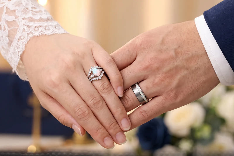 Her white opal engagement ring beside his brushed band with white opal inlay