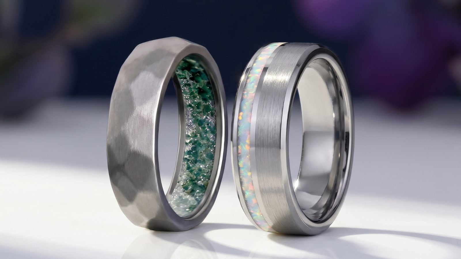 A moss agate tungsten band and an opal-inlay tungsten band side by side