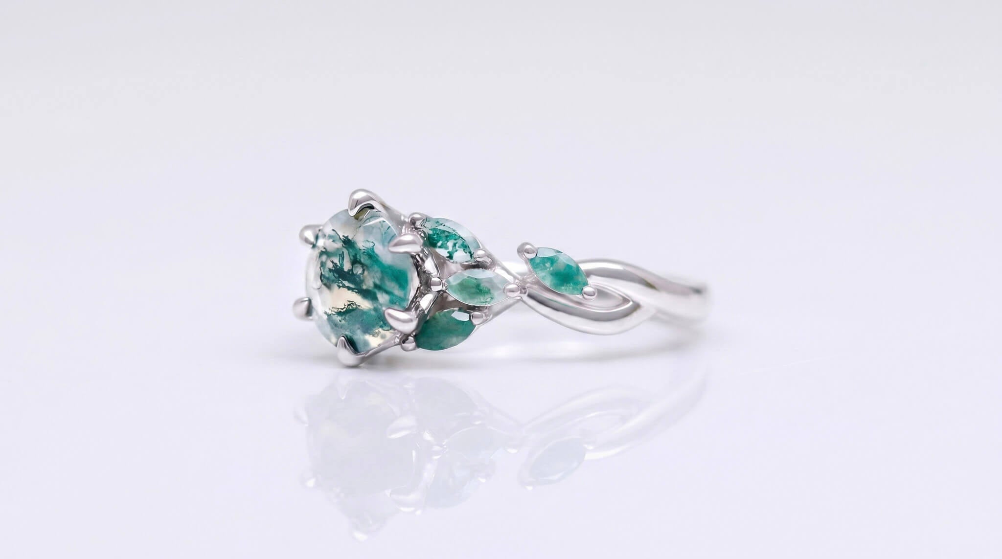 Moss agate alternative engagement ring in sterling silver on a neutral background