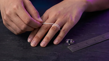 Measuring ring size at home with string and a ruler beside a ring