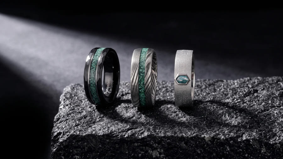 Most durable ring metals compared: tungsten carbide, damascus steel, and sterling silver men's rings on dark stone