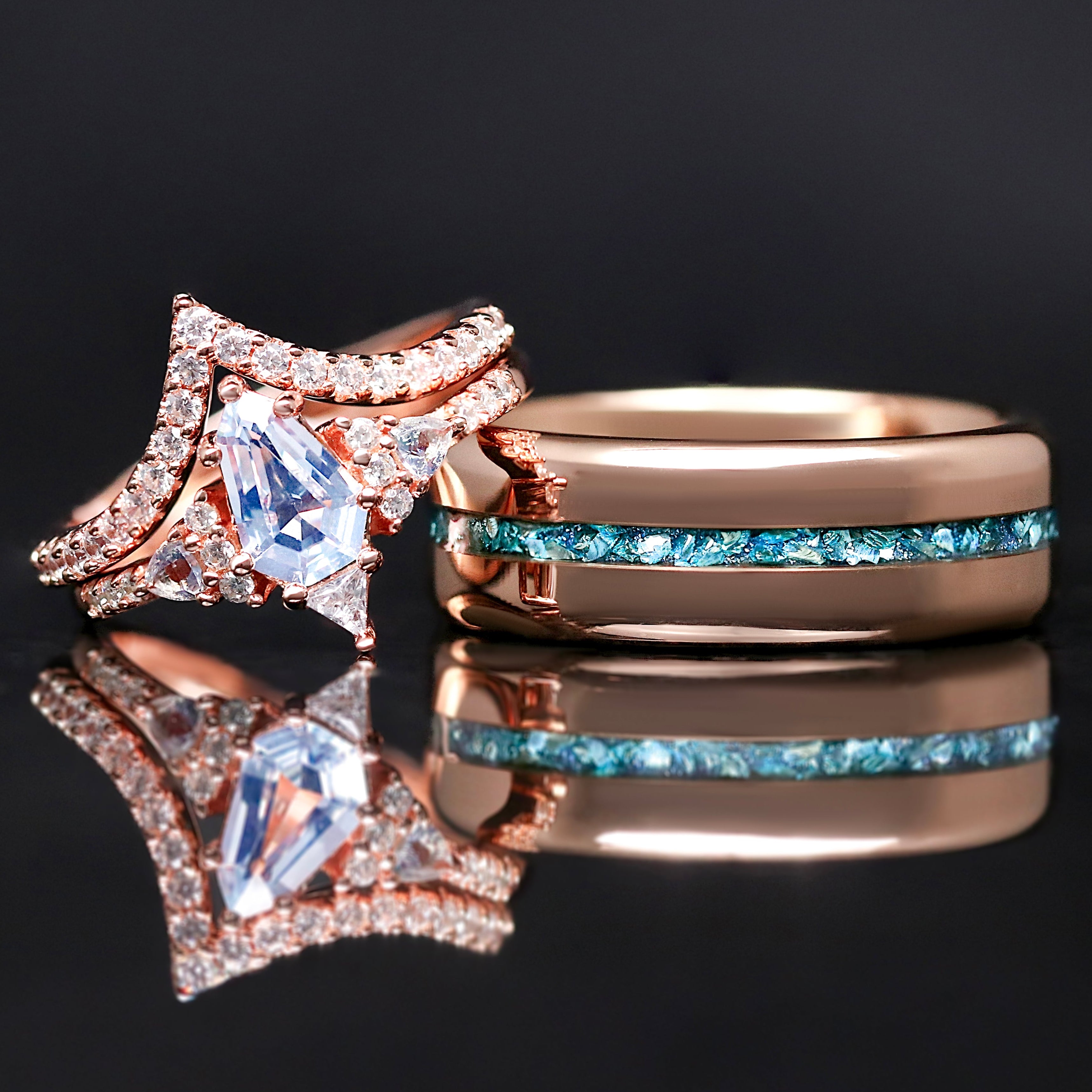 Two rose gold rings with gemstones on a reflective surface