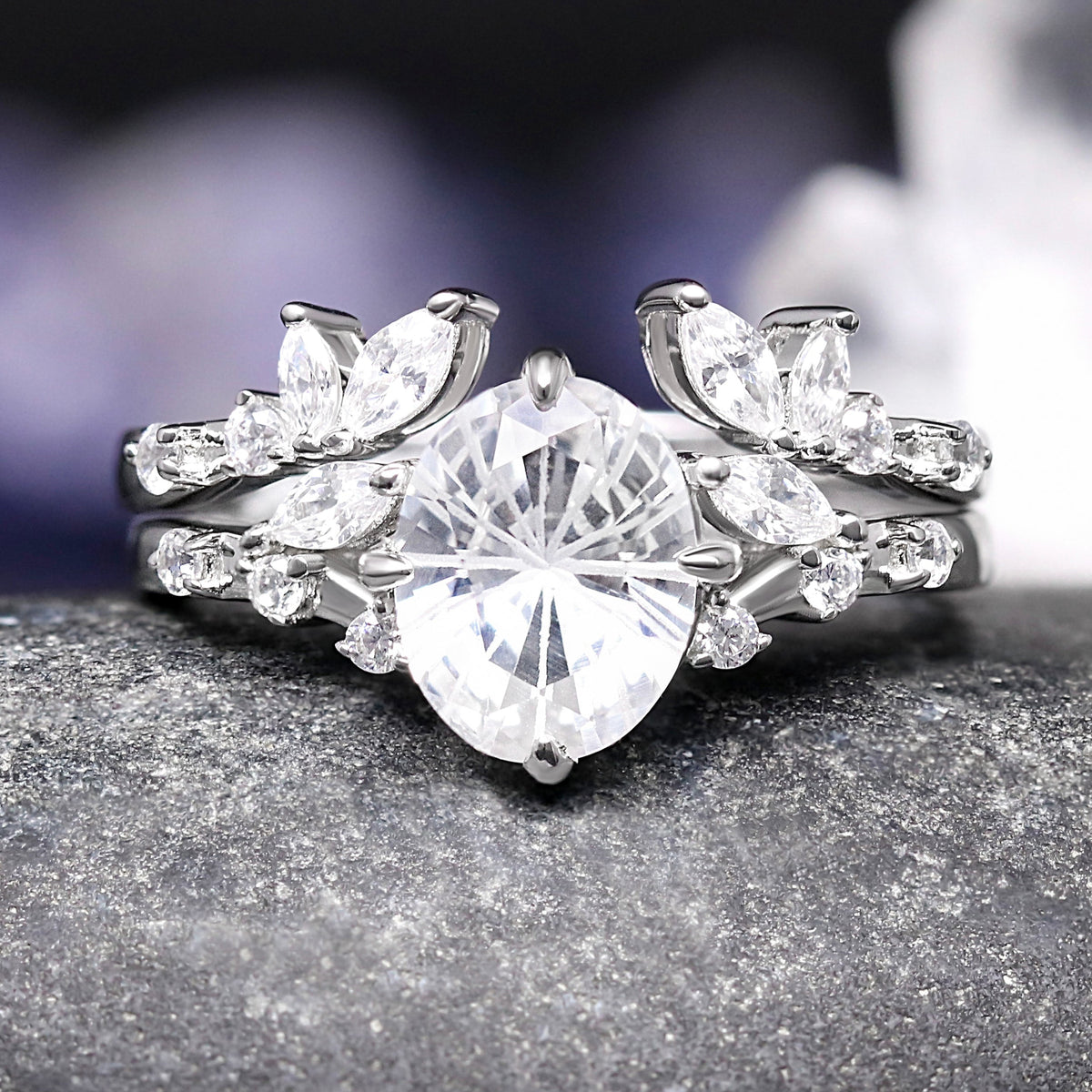 Silver ring with a large central diamond and smaller diamonds on a dark surface
