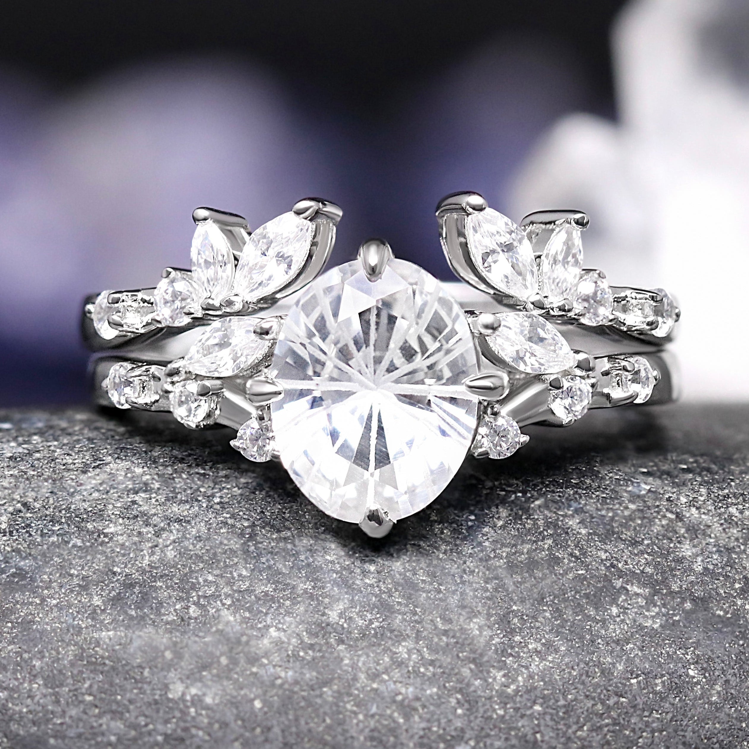 Silver ring with a large central diamond and smaller diamonds on a dark surface