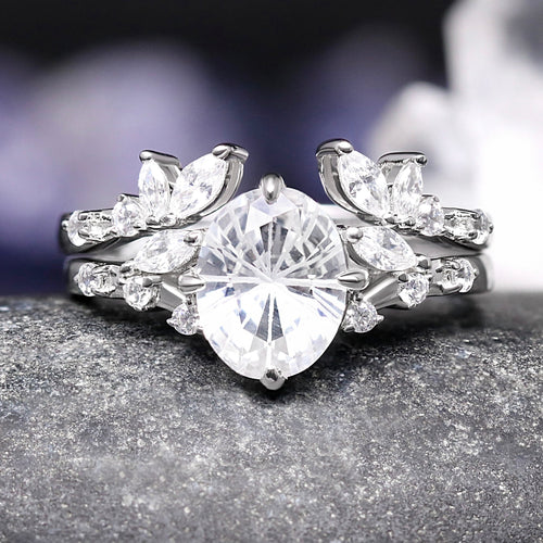 Silver ring with a large central diamond and smaller diamonds on a dark surface