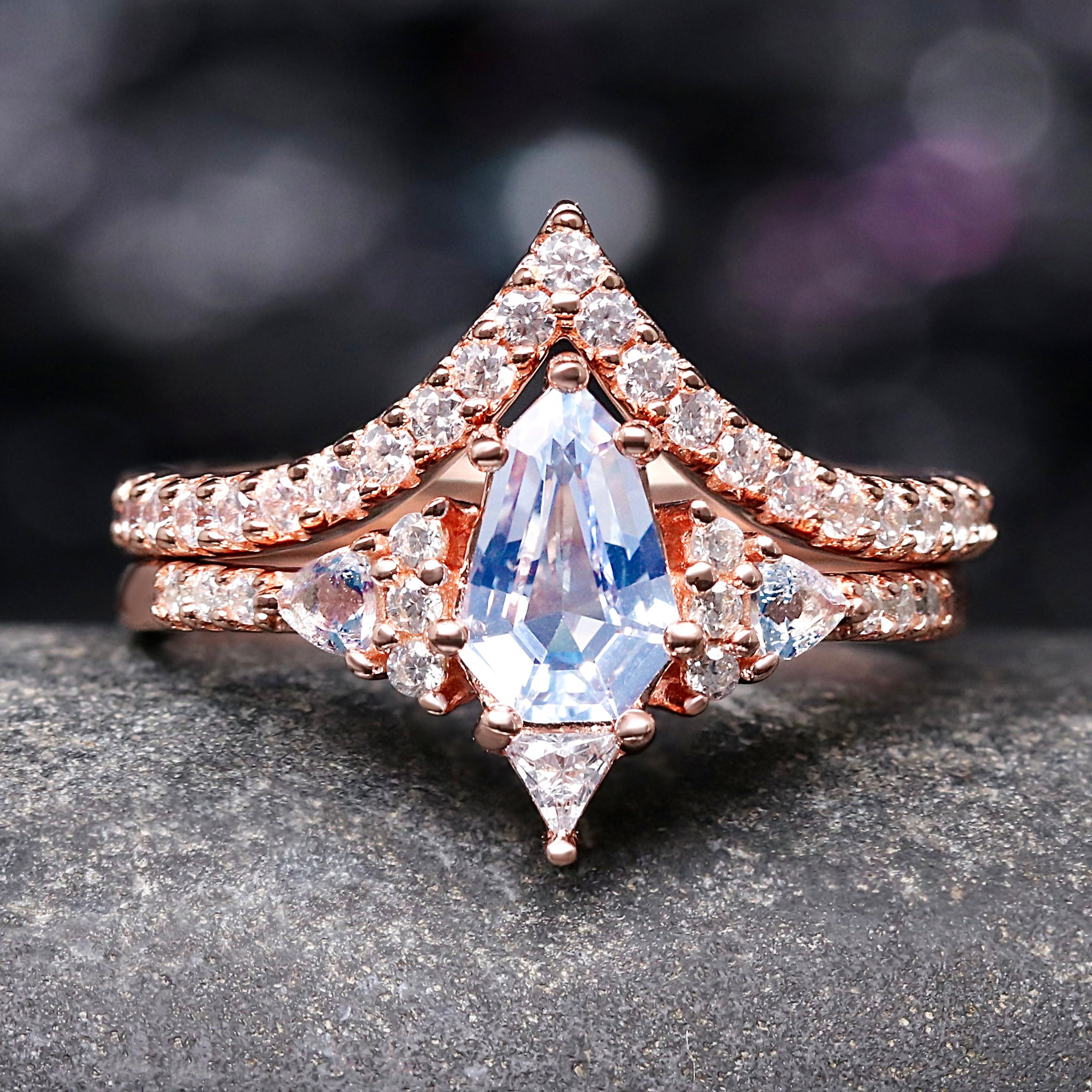 Rose gold ring with a large central aquamarine and smaller diamonds on a dark surface