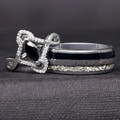 Sterling silver marquise black stone ring with a white stone halo beside a wide silver tungsten band