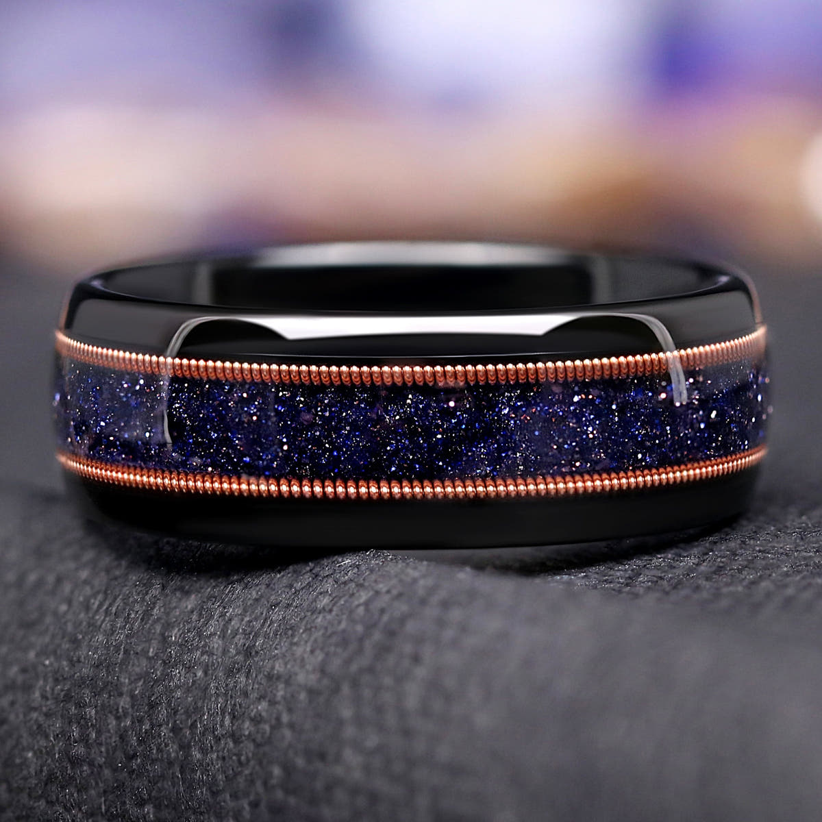Men's 8mm black tungsten band with blue sandstone and rose gold guitar string inlay, close-up