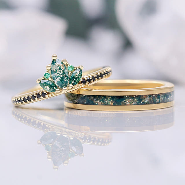 Gold moss agate crown ring leaning on a gold band with moss agate inlay, angled view