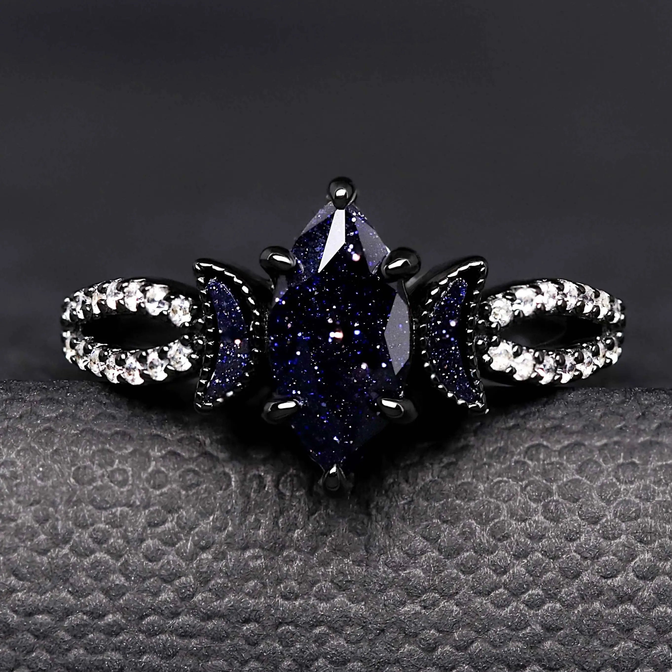 Black diamond ring with white gemstones on a textured gray surface